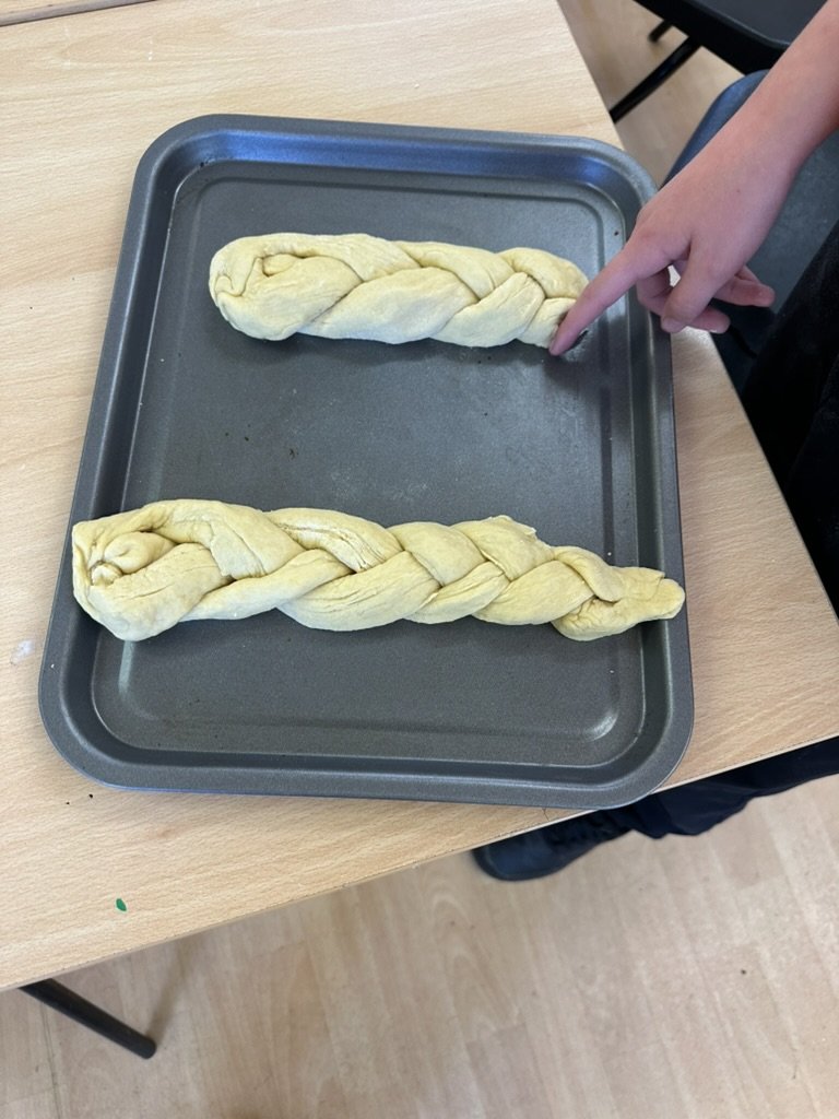 Two plaited loaves of dough on a baking tray, ready to bake